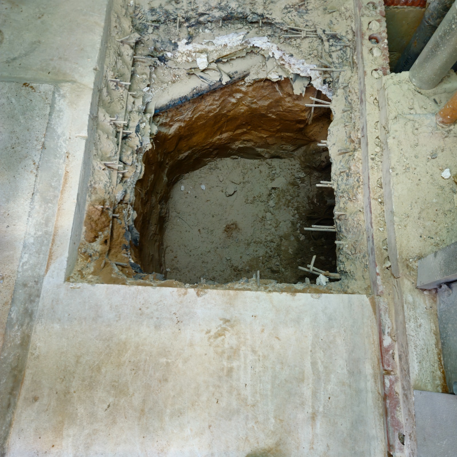 Hand excavation through the broken-out reinforced slab at Watts Gallery, Guildford