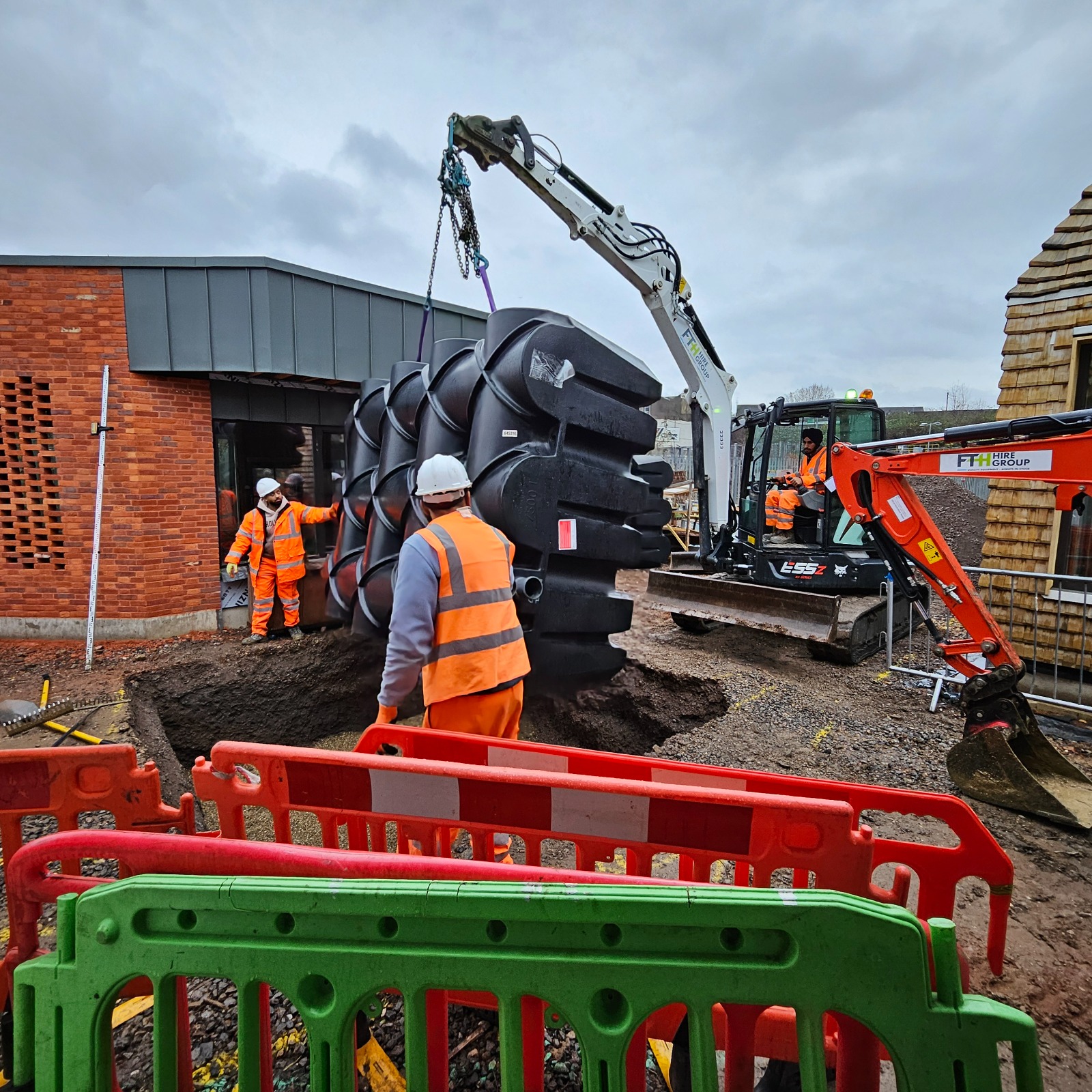 Klargester rainwater harvesting tank being lifted into position between finished buildings